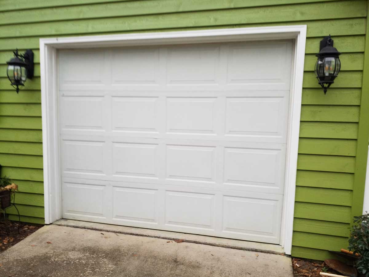 "Before" image of white garage door on a green house